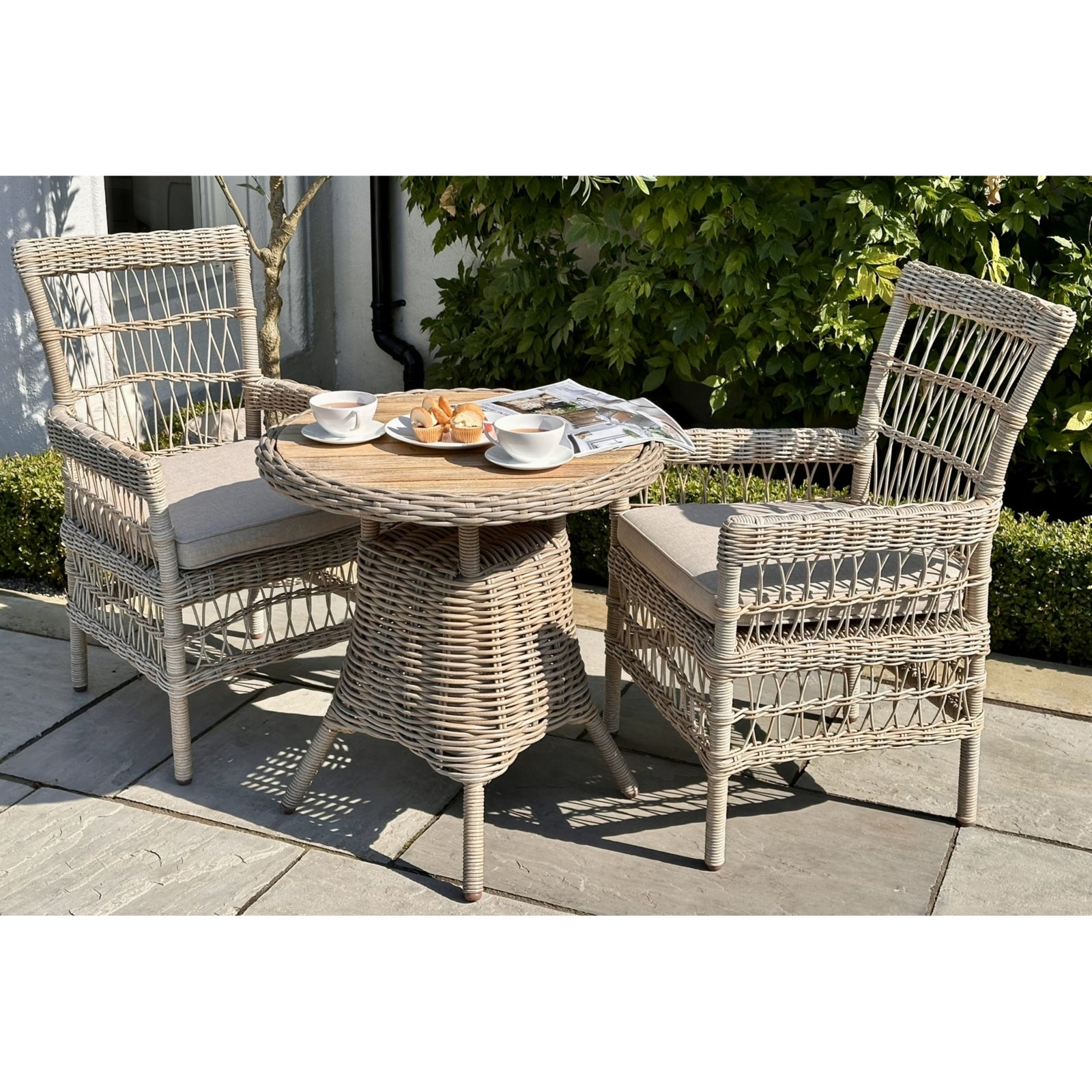 Wicker outdoor furniture set with a small table and two chairs on a patio.