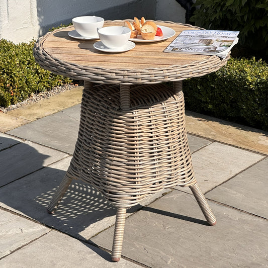 Wicker side table with tea set and newspaper on a patio