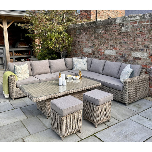 Outdoor patio set with sectional sofa, coffee table, and ottomans on a stone patio.