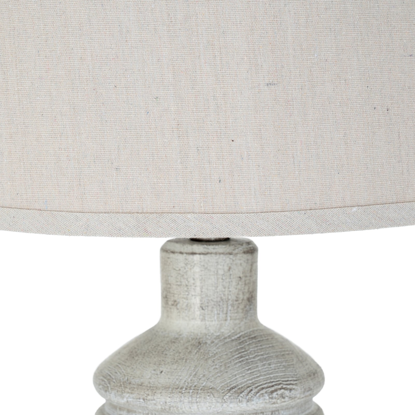 Close-up of a textured lamp base with a light gray fabric lampshade on a white background
