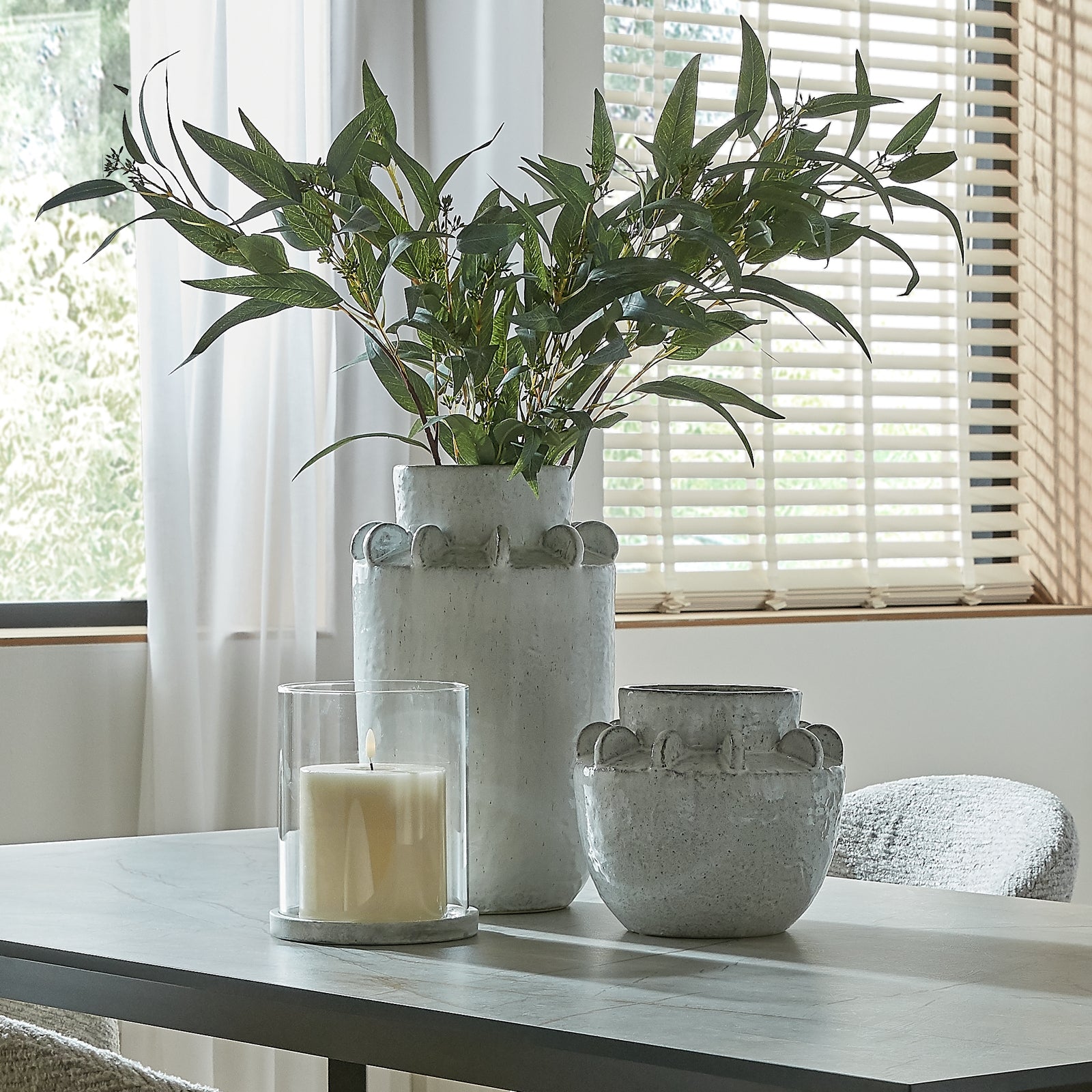 Decorative vases with a candle on a table near a window