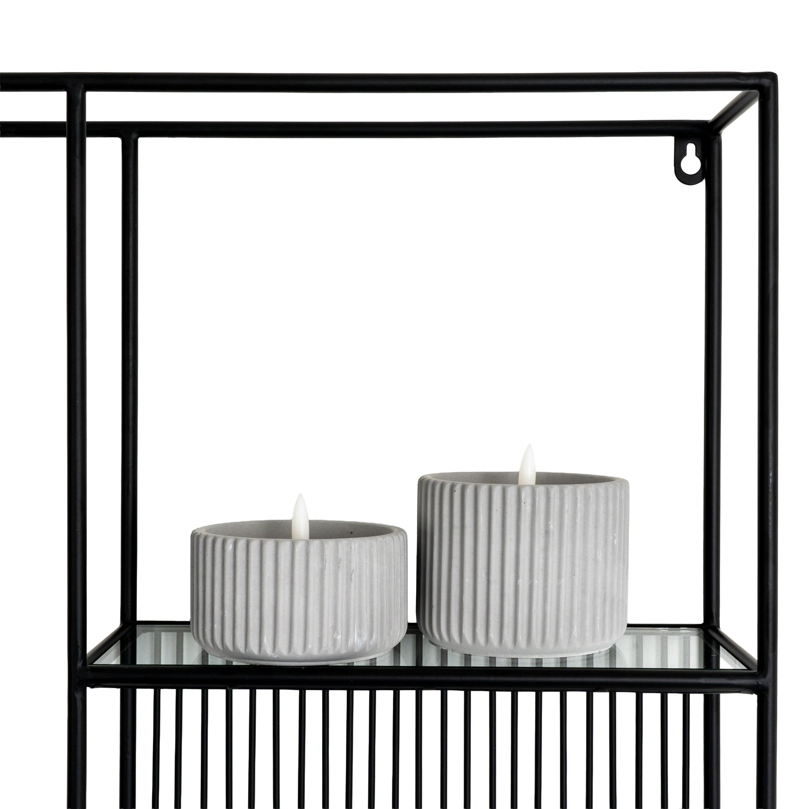 Two gray candles in holders on a black metal shelf with a white background