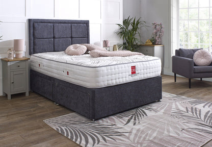 Bed with gray upholstered headboard and white mattress in a bedroom setting.