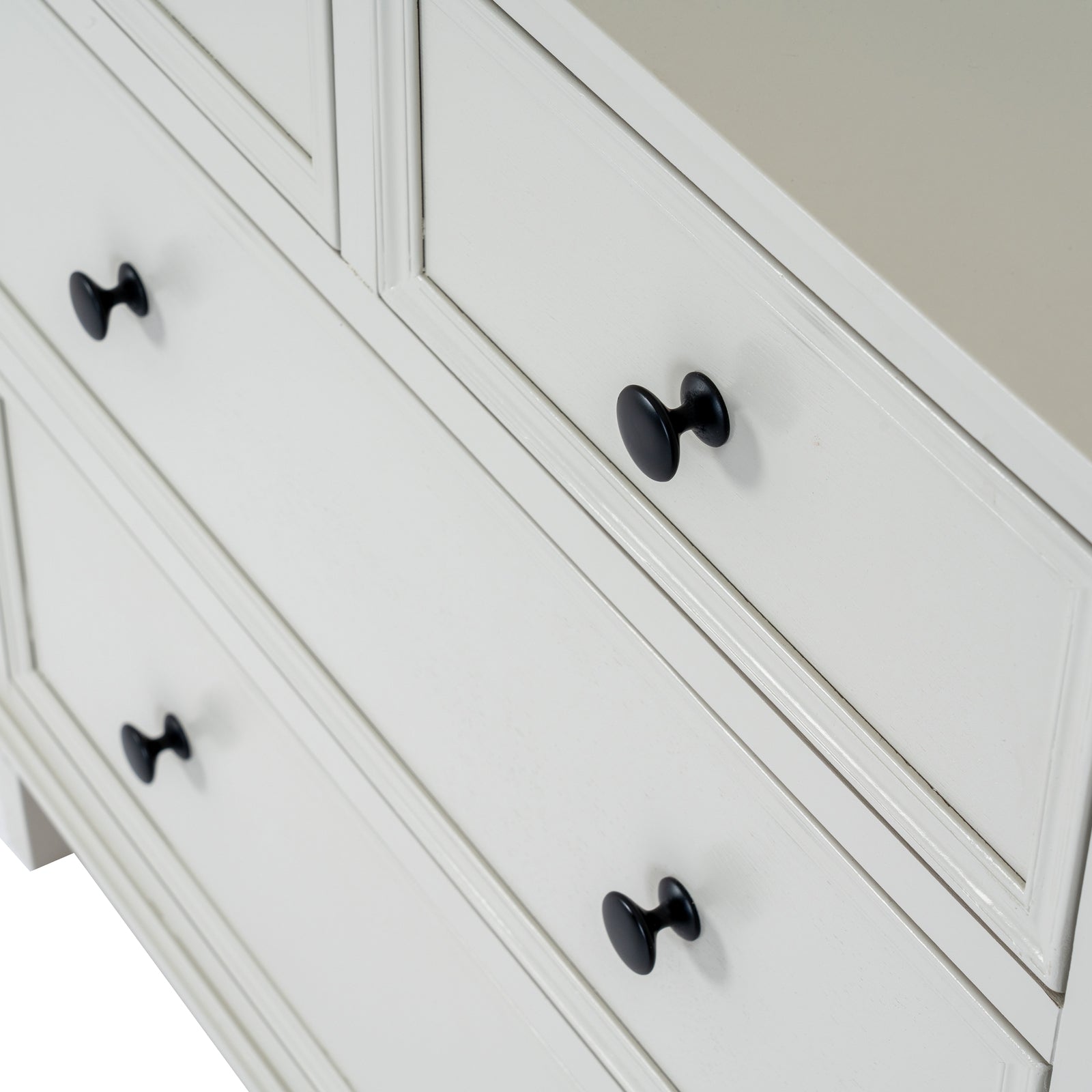 White dresser with black knobs on a neutral background