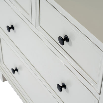 White dresser with black knobs on a neutral background