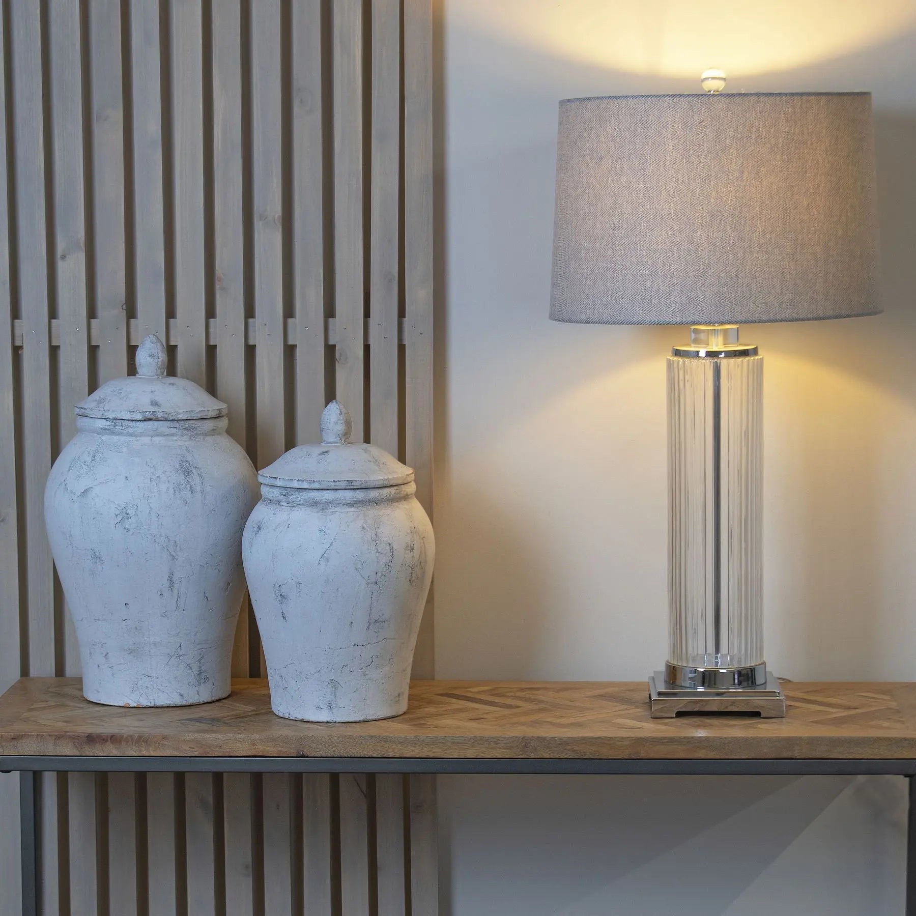 Decorative lamp and jars on a wooden surface with a neutral background