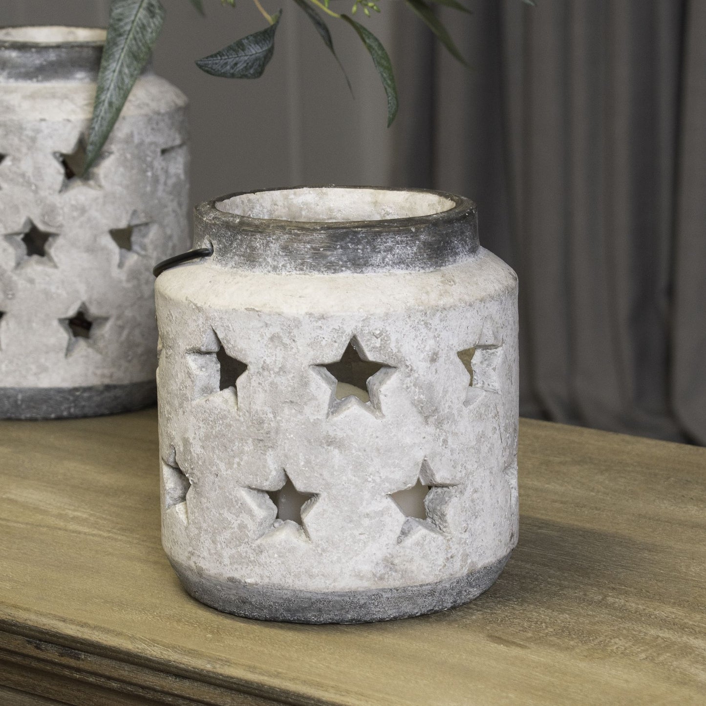 Decorative stone lantern with star cutouts on a wooden surface.