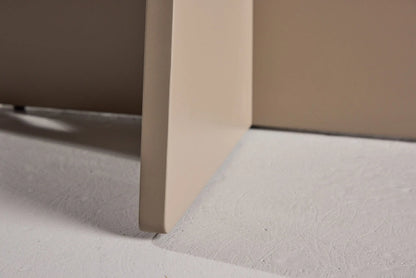 Close-up of a corner of a beige piece of furniture on a light gray floor.