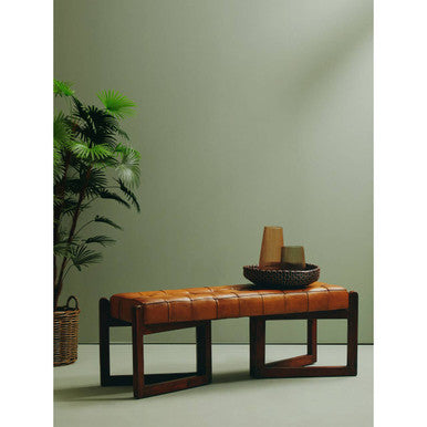 Brown leather bench with decorative items against a green wall