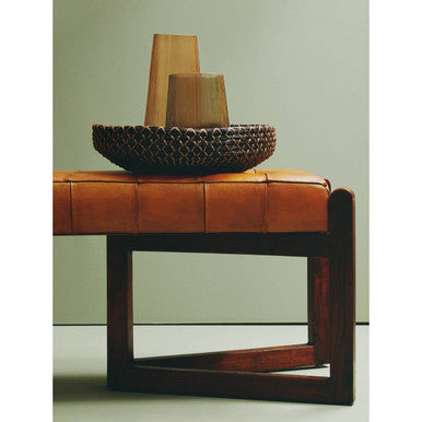 Decorative bowl on a brown leather ottoman with a plain background
