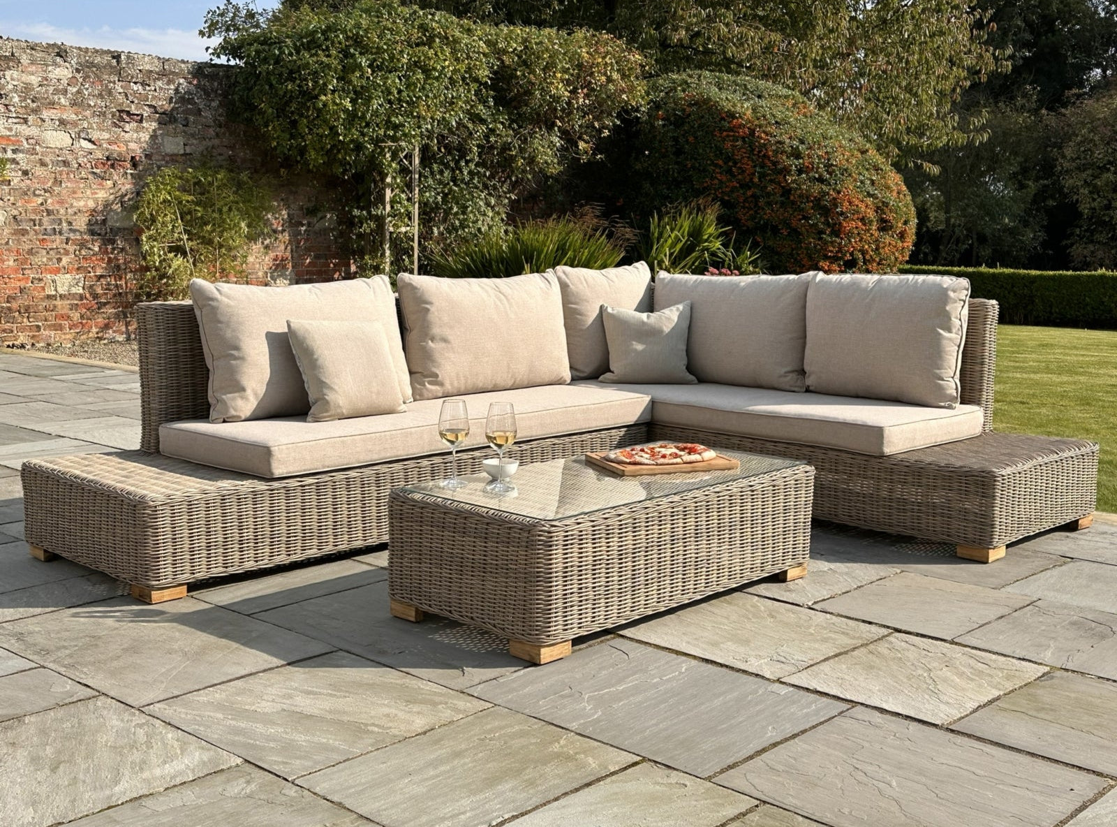 Outdoor patio furniture set with a glass table on a stone patio.