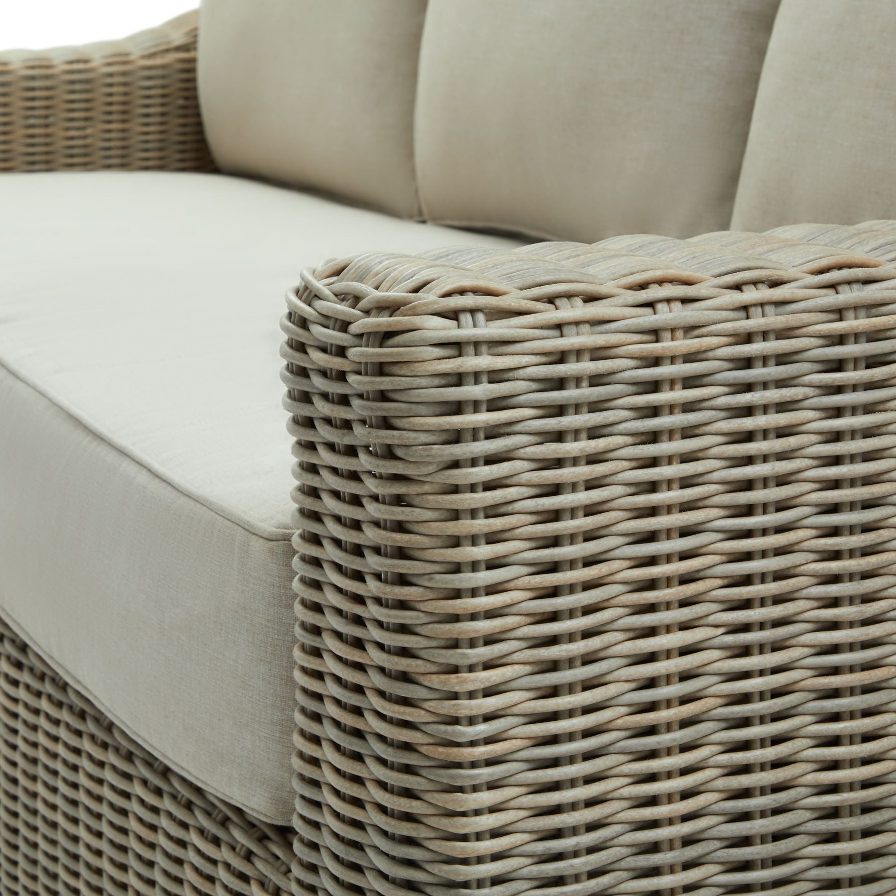 Close-up of a wicker outdoor sofa with beige cushions