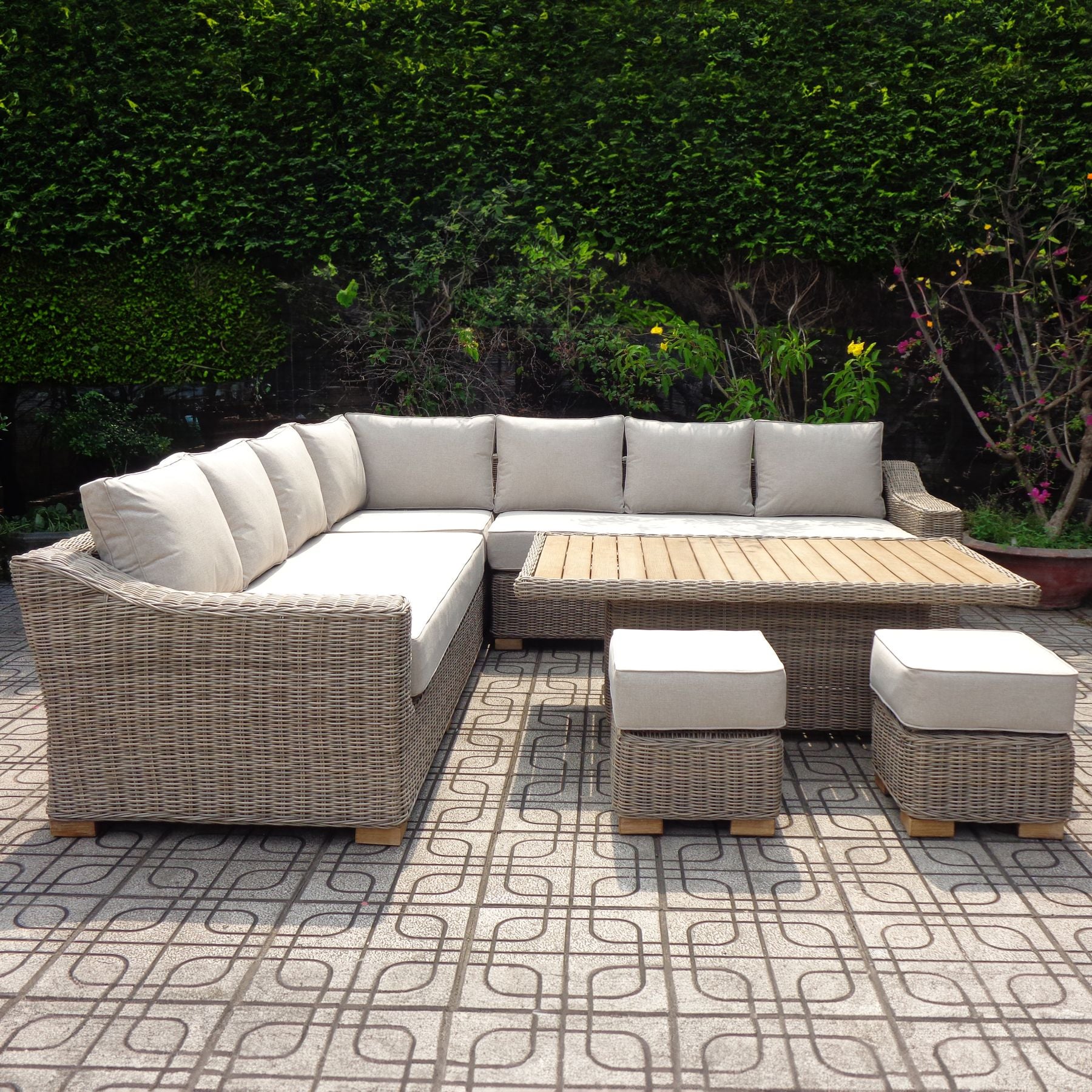 Outdoor patio furniture set with a sectional sofa and ottomans on a patterned patio.
