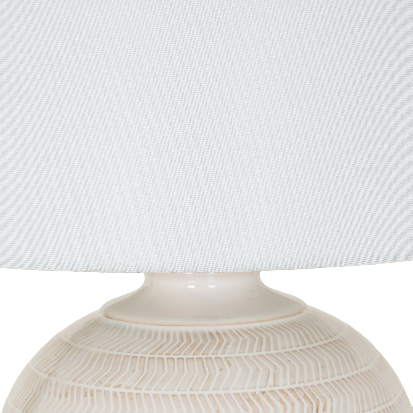 Close-up of a textured ceramic lamp base with a white lampshade on a light gray background