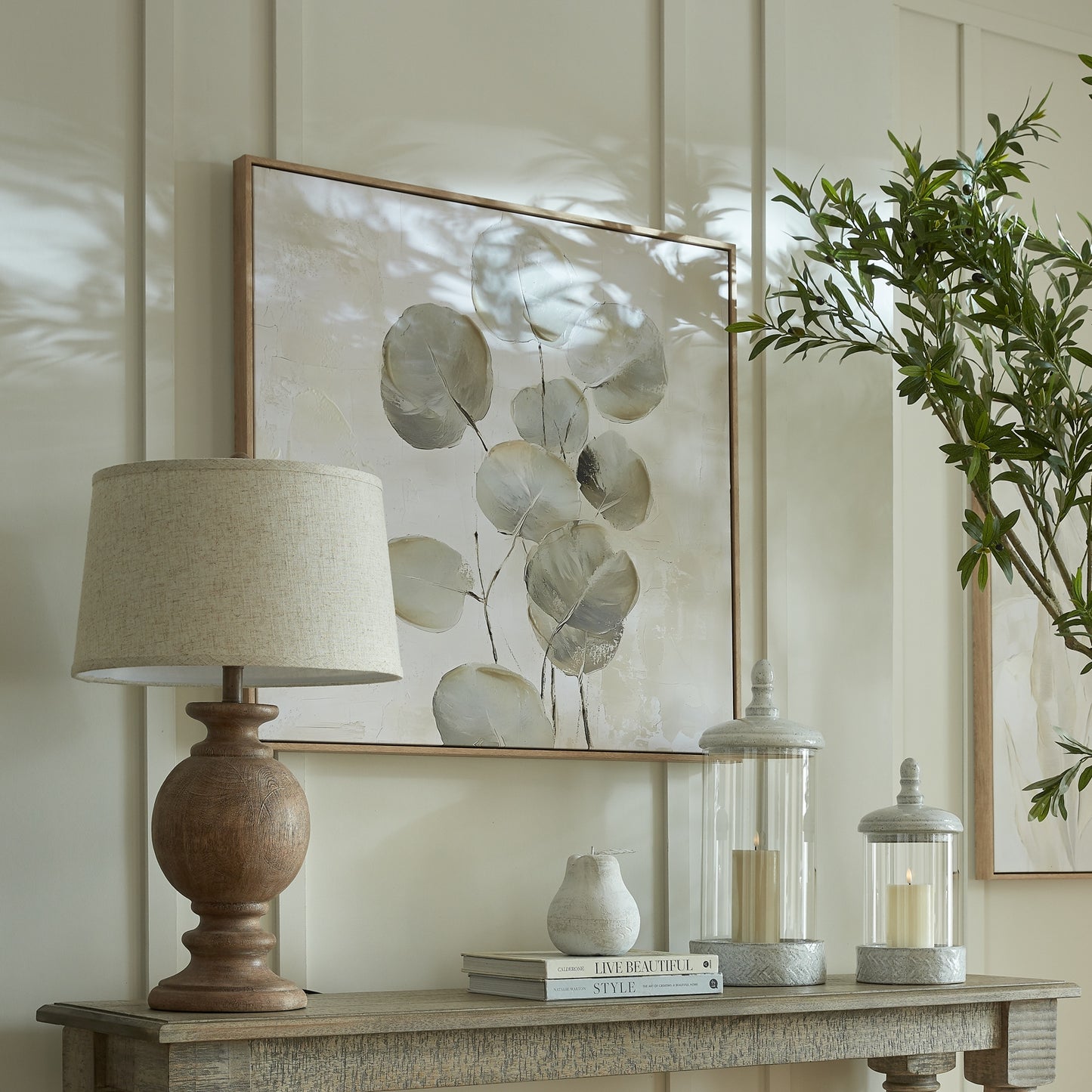 Decorative table setting with a lamp, books, and candle holders on a wooden surface.