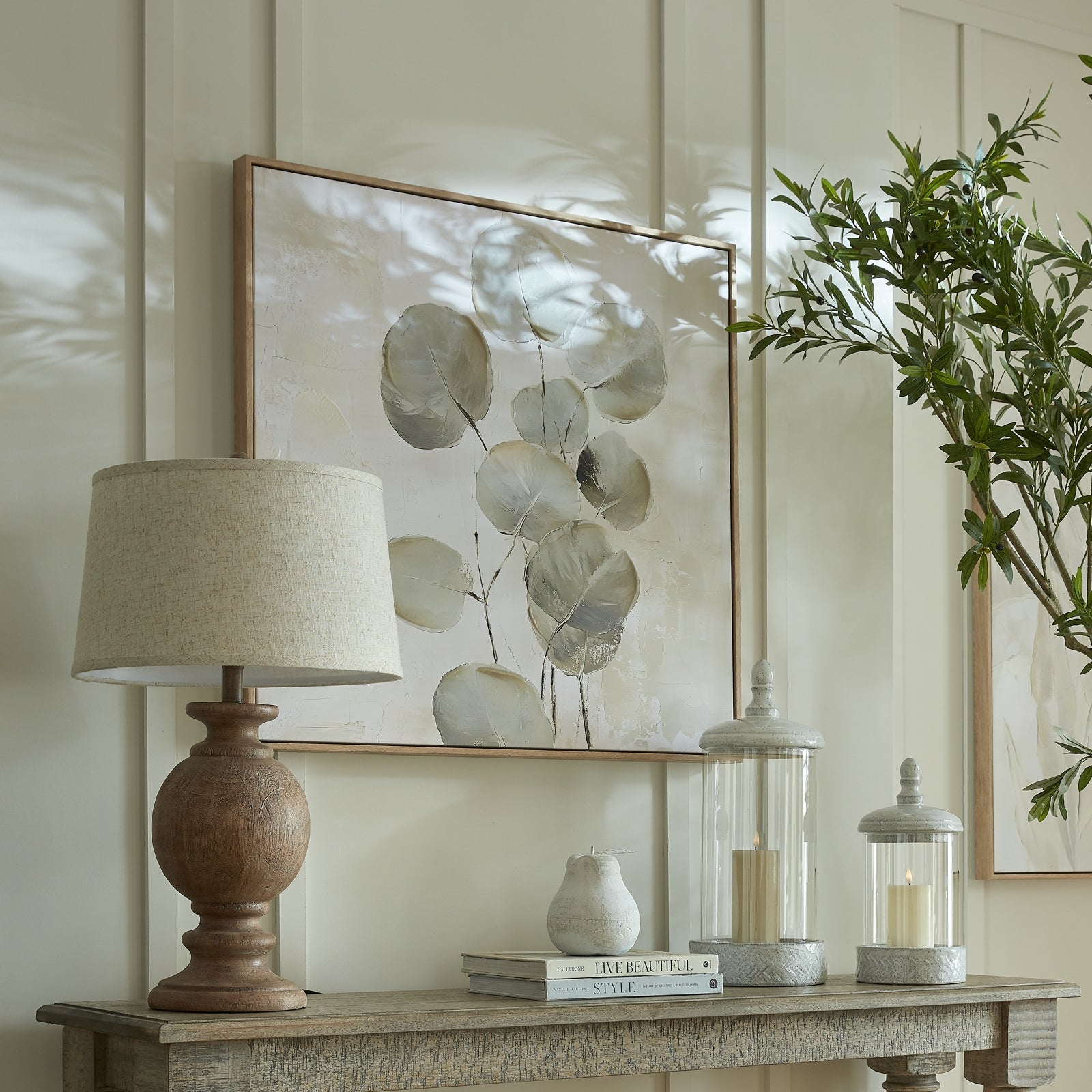 Decorative table setting with a lamp, books, and candle holders on a wooden surface.