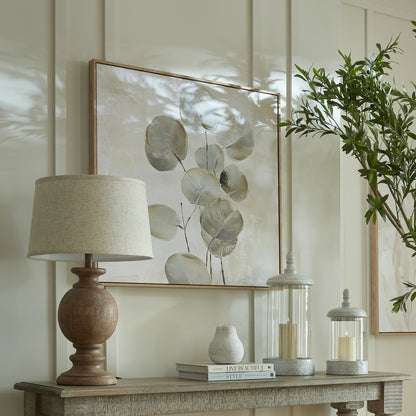 Decorative table setting with a lamp, books, and candle holders on a wooden surface.