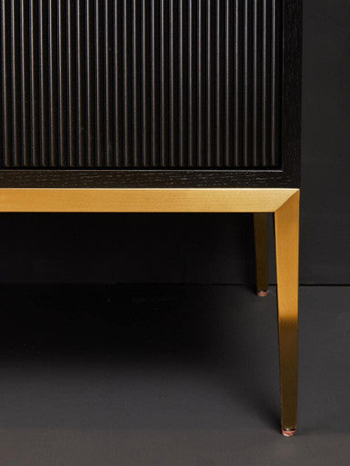 Close-up of a black cabinet with gold legs on a dark background