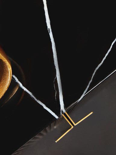 Close-up of a black marble surface with white veins and a gold accent.