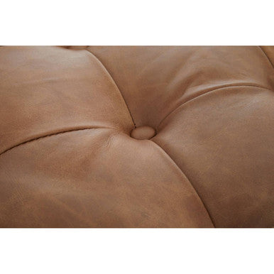 Close-up of a brown leather cushion with tufted design