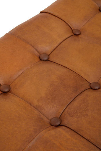 Close-up of a brown leather ottoman with tufted design