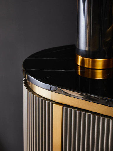 Close-up of a luxurious black and gold cylindrical object with ribbed design on a dark background
