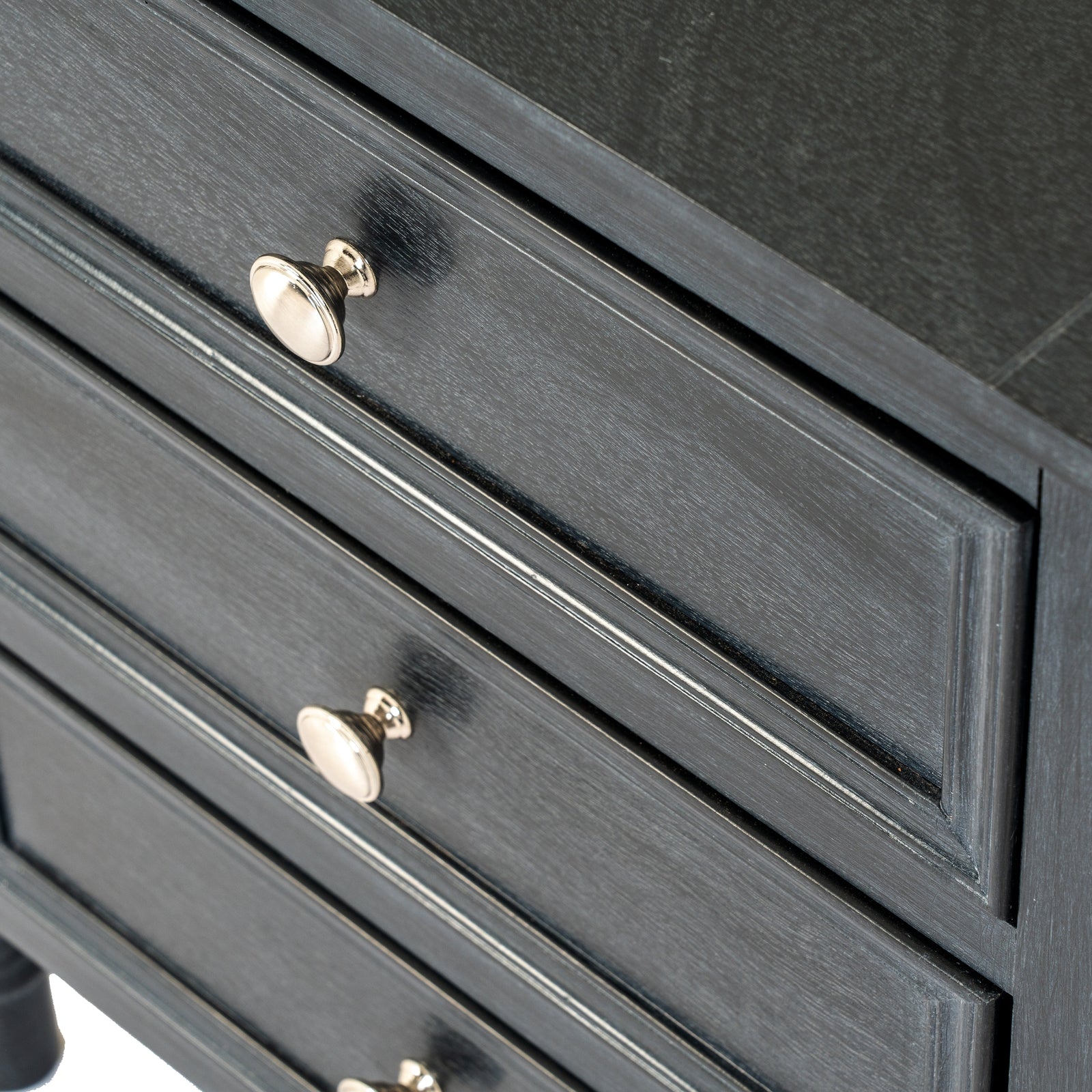 Close-up of a dark gray dresser with gold knobs on a white background