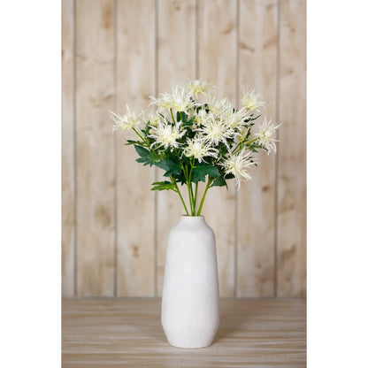 White vase with artificial flowers against a wooden panel background