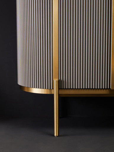Cylindrical cabinet with striped pattern and gold accents on a dark background