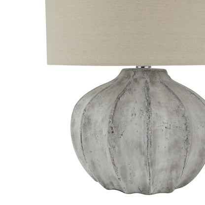Table lamp with textured gray base and beige lampshade on a white background