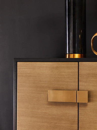 Wooden cabinet with gold handle against a black background