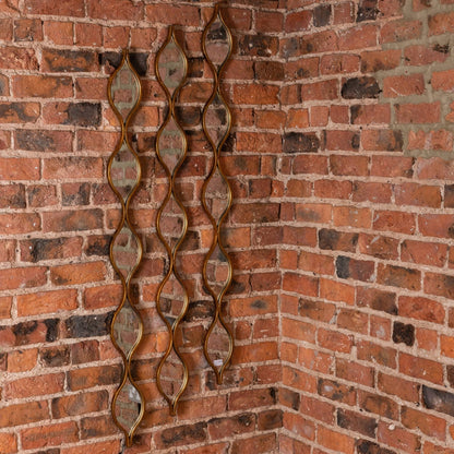 Decorative wall mirror with wavy design on a brick wall