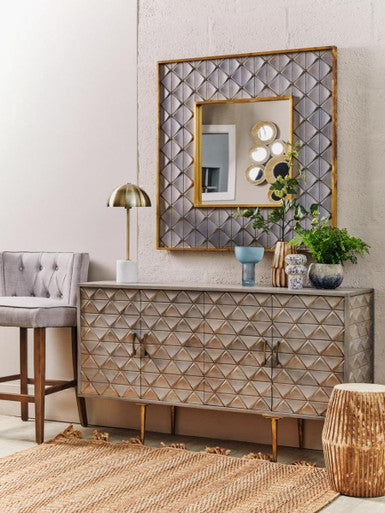 Decorative console table with mirror and lighting fixture in a room setting.