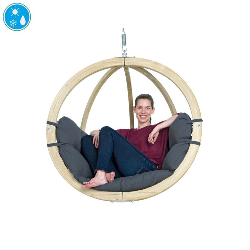 Person sitting in a circular hanging chair with a neutral background