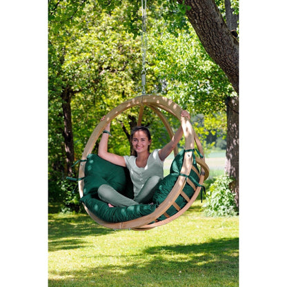 Person sitting in a green and wooden hanging chair in a park.