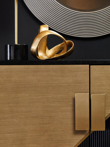 Gold abstract sculpture on a wooden surface with a black background
