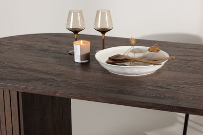 Wooden table with a bowl, candles, and glasses on a neutral background