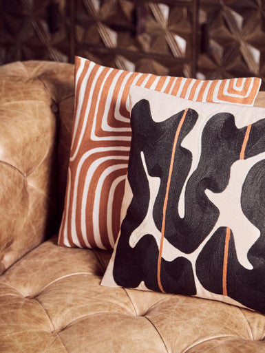 Decorative pillows with abstract patterns on a brown couch
