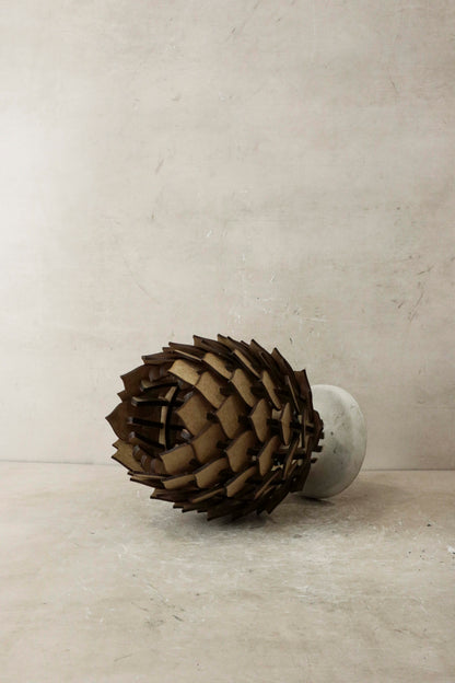 Decorative object resembling a pine cone on a plain background