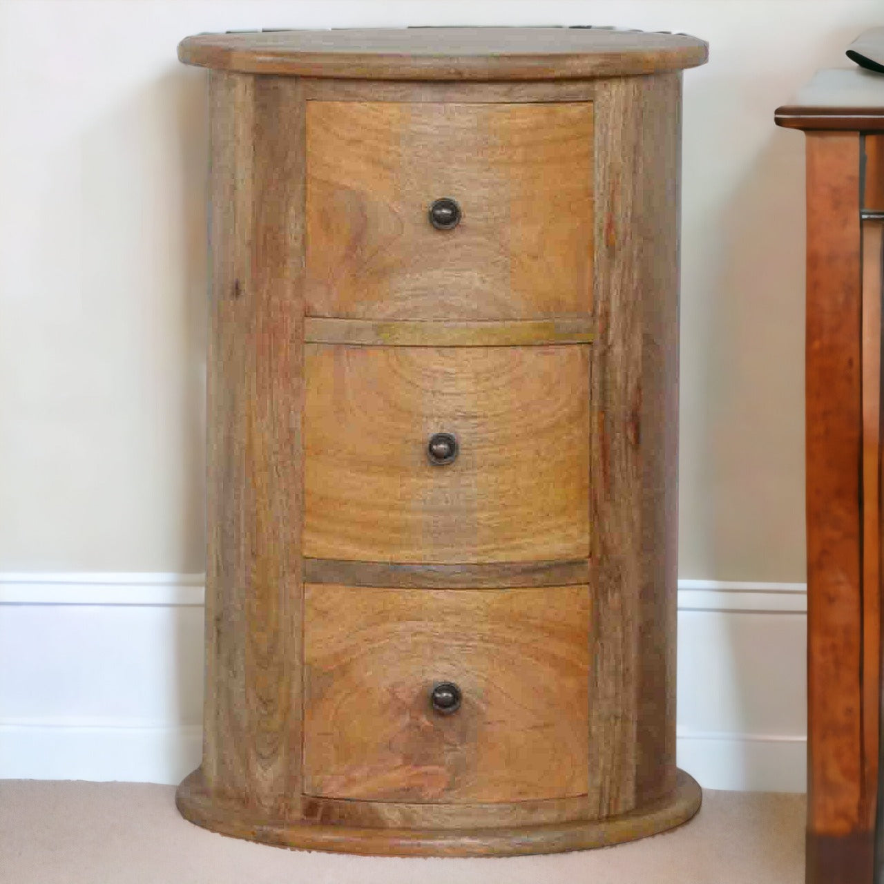 Wooden cylindrical cabinet with three drawers against a white wall.