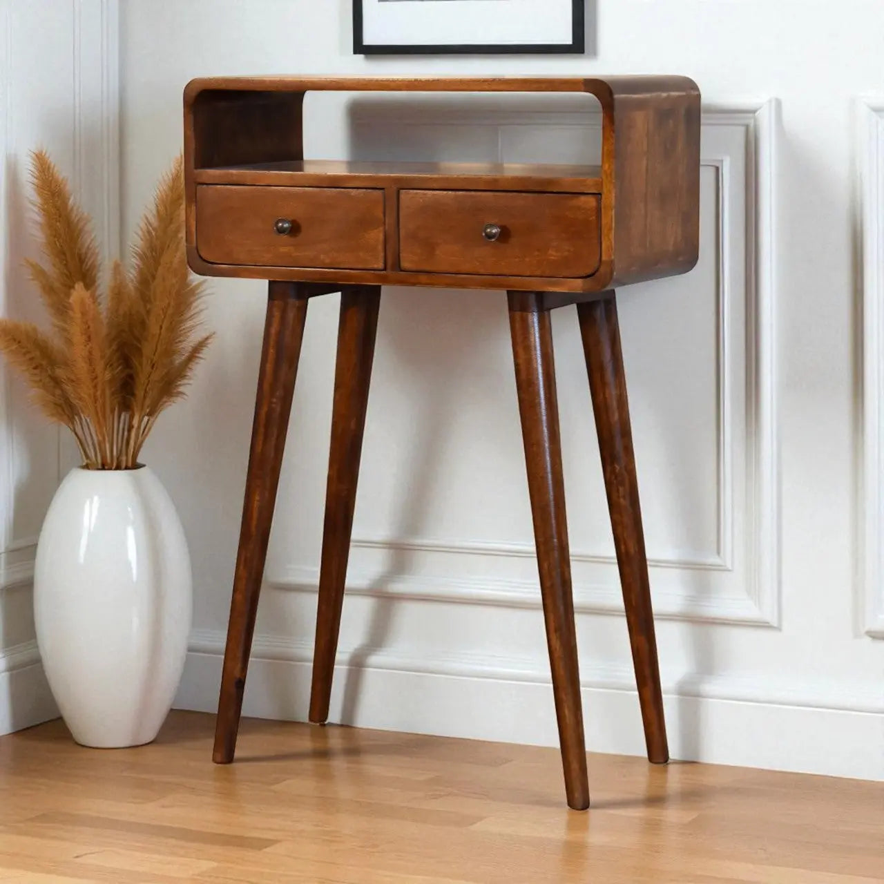Wooden side table with two drawers in a room setting with a vase and decorative plant.