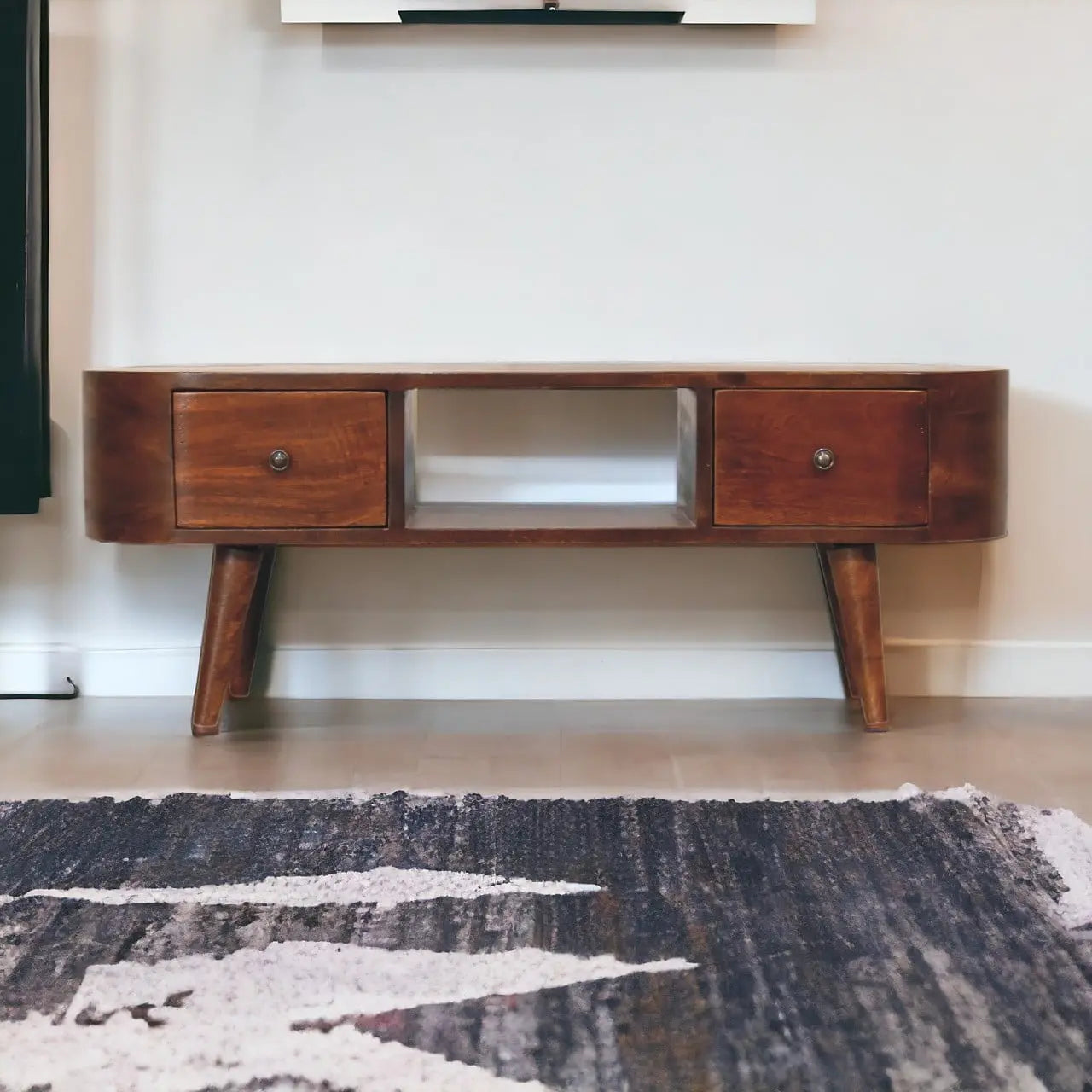 Wooden TV stand with two drawers in a room with a rug on the floor.