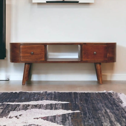 Wooden TV stand with two drawers in a room with a rug on the floor.
