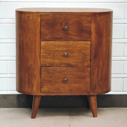 Wooden side table with three drawers against a tiled wall.