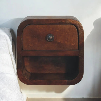 Wooden nightstand with a single drawer against a white wall