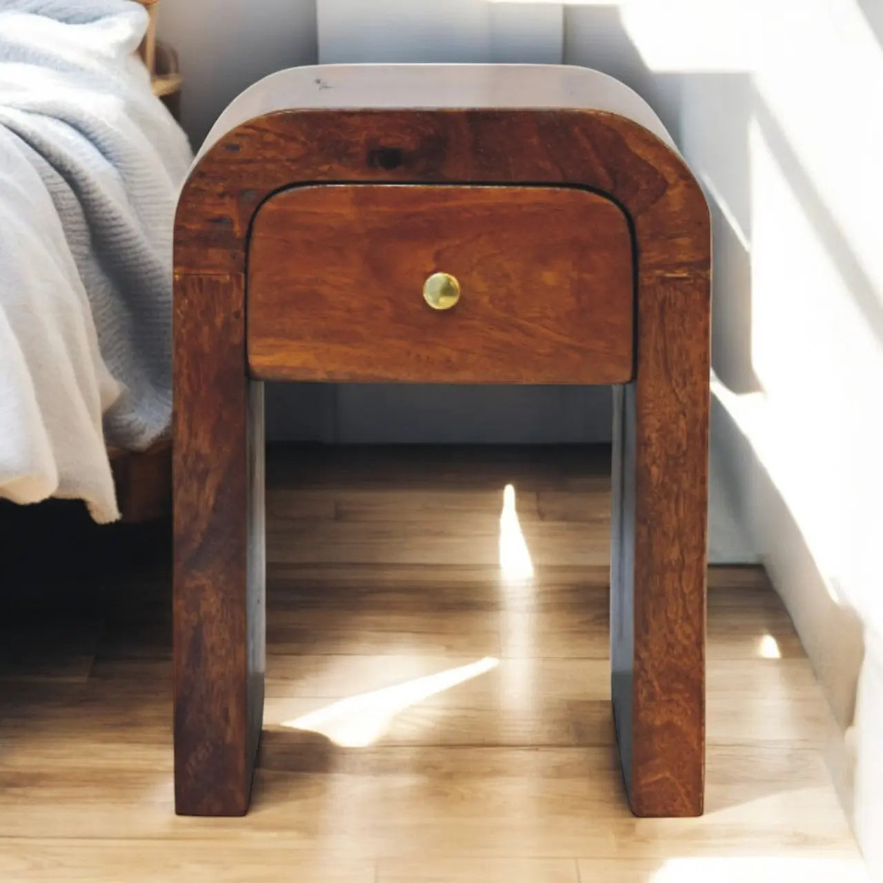 Wooden nightstand with a single drawer next to a bed