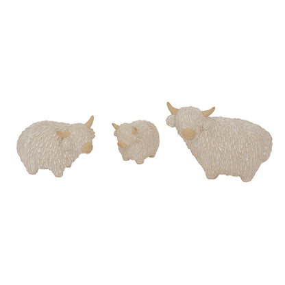 Three small beige sheep figurines on a white background
