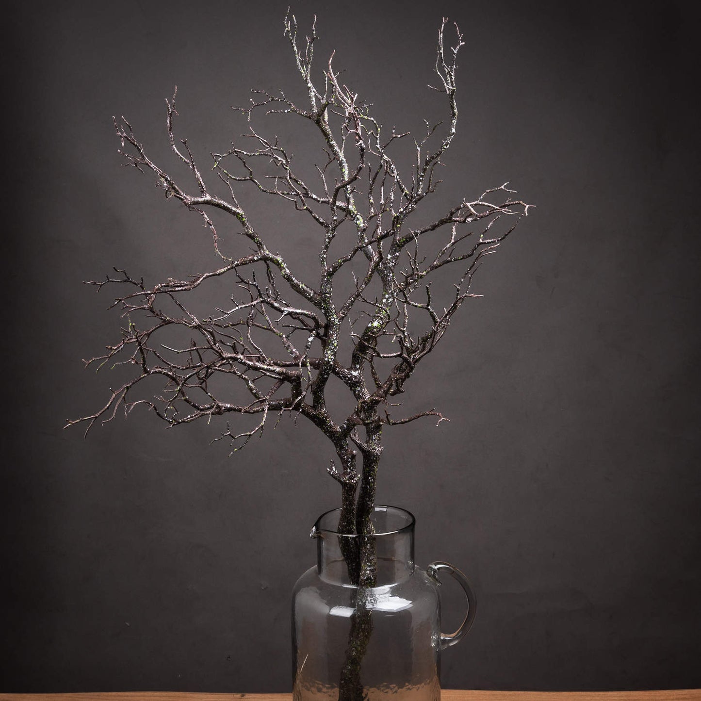 Decorative branch in a glass vase against a dark background