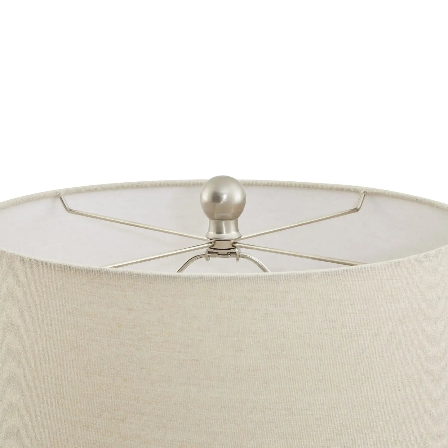 Close-up of a beige lampshade with a metallic finial on a white background