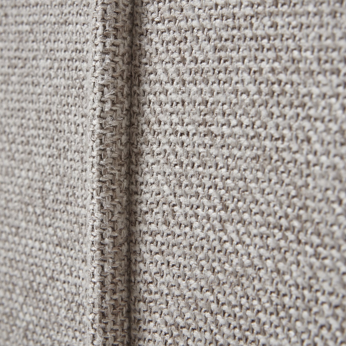 Close-up of textured beige fabric with a visible seam.